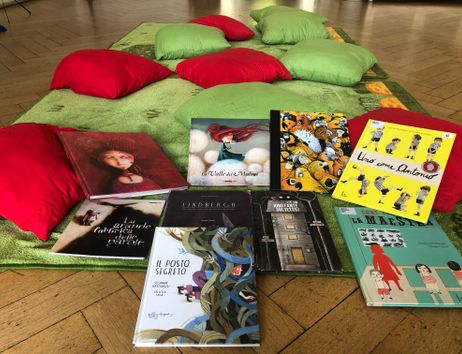 Spielteppich mit bunten Kissen und italienischen Kinderbüchern
