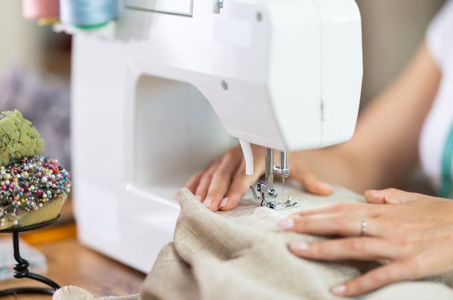 Nahaufnahme einer Person, die an einer Nähmaschine arbeitet.