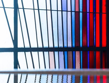 Buntglasfenster mit blau-roten Streifen und Spiegelung im Wasser.