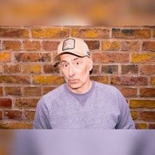 Person mit Baseballkappe vor einer Backsteinmauer.