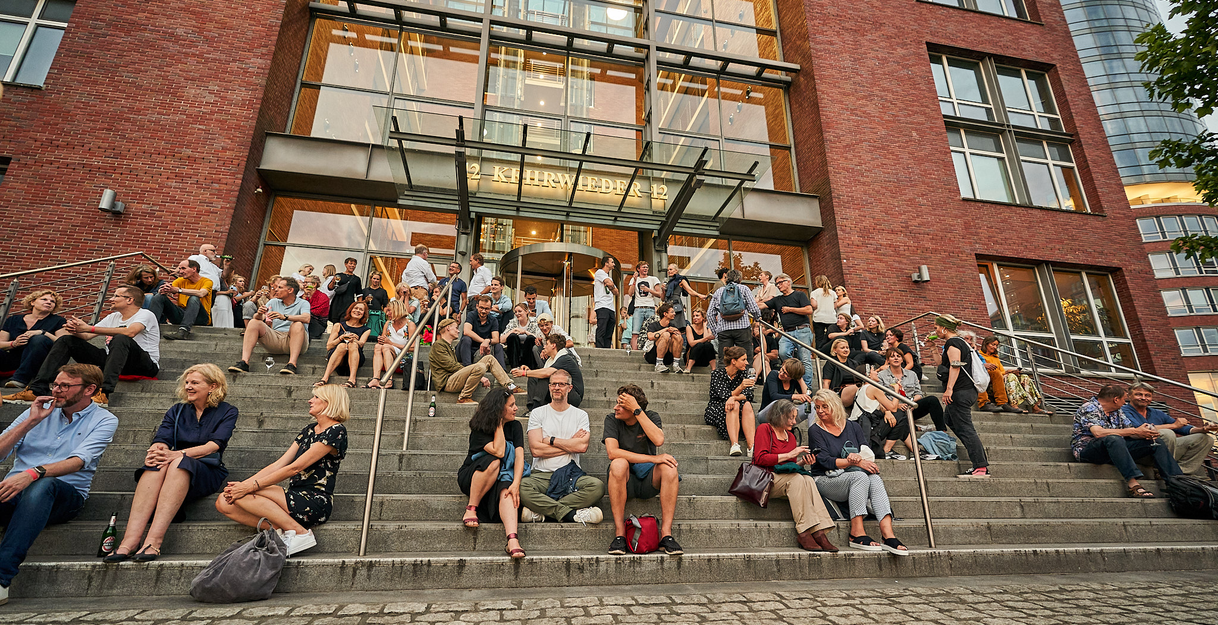 Außenansicht des KörberForums mit Menschen, die davor auf den Treppenstufen sitzen