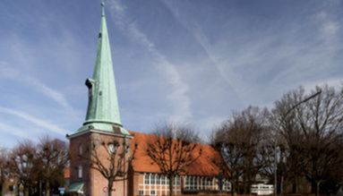 Kirche St. Johannis in Hamburg-Eppendorf mit spitzem Turm und rotem Ziegeldach.