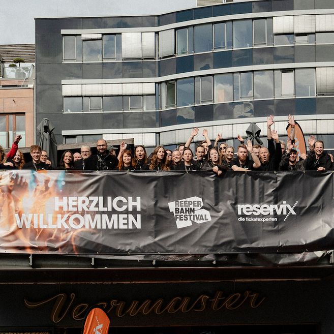 Gruppe von Menschen steht hinter einem Banner mit der Aufschrift 'Herzlich Willkommen' beim Reeperbahn Festival.