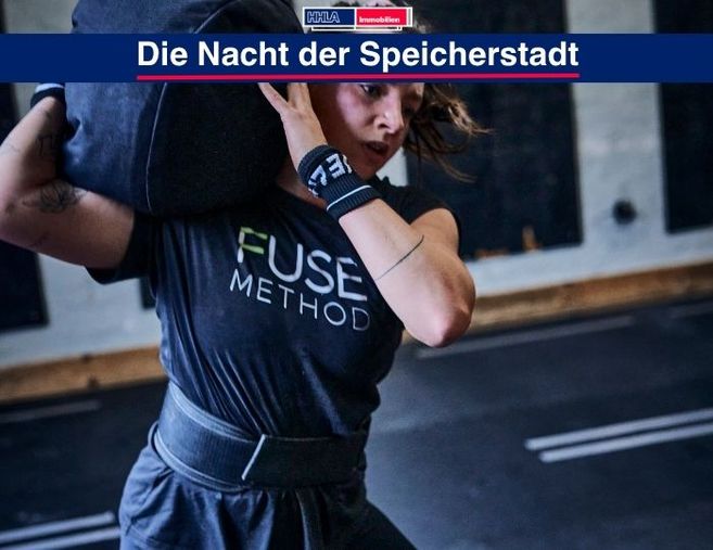 Eine Frau hebt einen schweren Sandsack in einem Fitnessstudio.