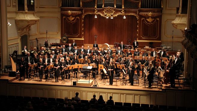 Ein symphonisches Blasorchester auf einer Bühne in einem Konzertsaal.