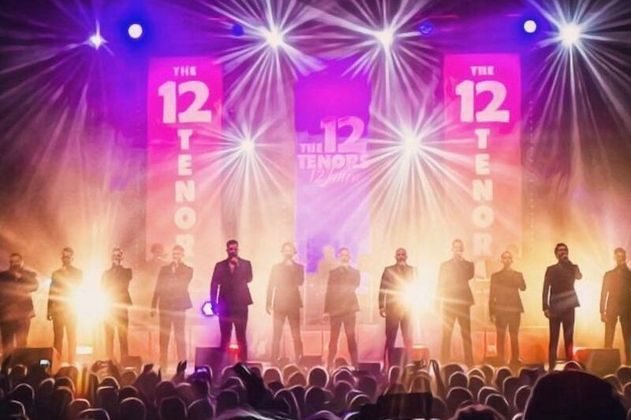 Zwölf Tenöre auf einer Bühne mit bunten Lichtern und Publikum.