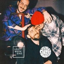 Vier Männer posieren lächelnd, einer trägt eine rote Mütze.