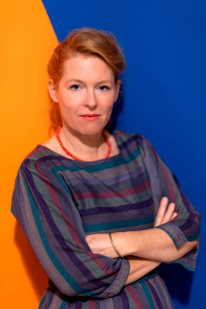 Frau vor einem zweifarbigen Hintergrund in Blau und Orange.