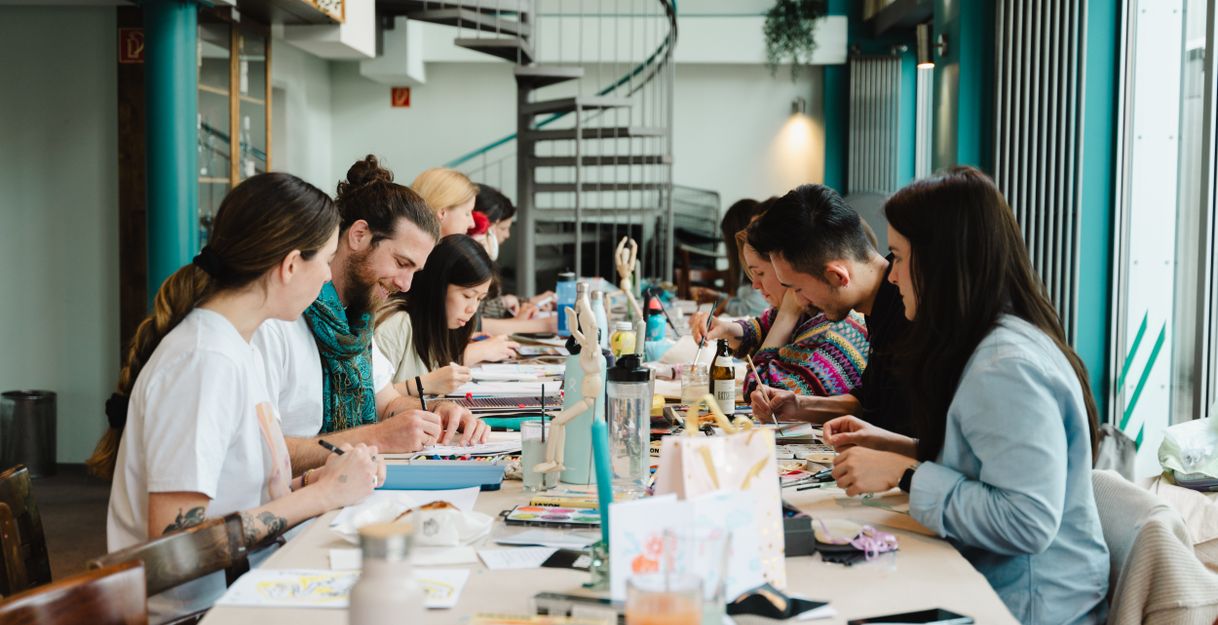 Menschen beim gemeinsamen kreativ sein an eine langen Tafel