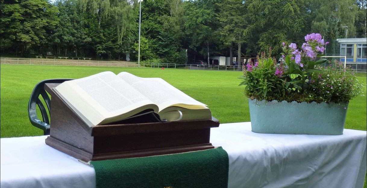 Aufgeschlagene Bibel und Blumenkorb auf einem Altar auf dem Fußballfeld