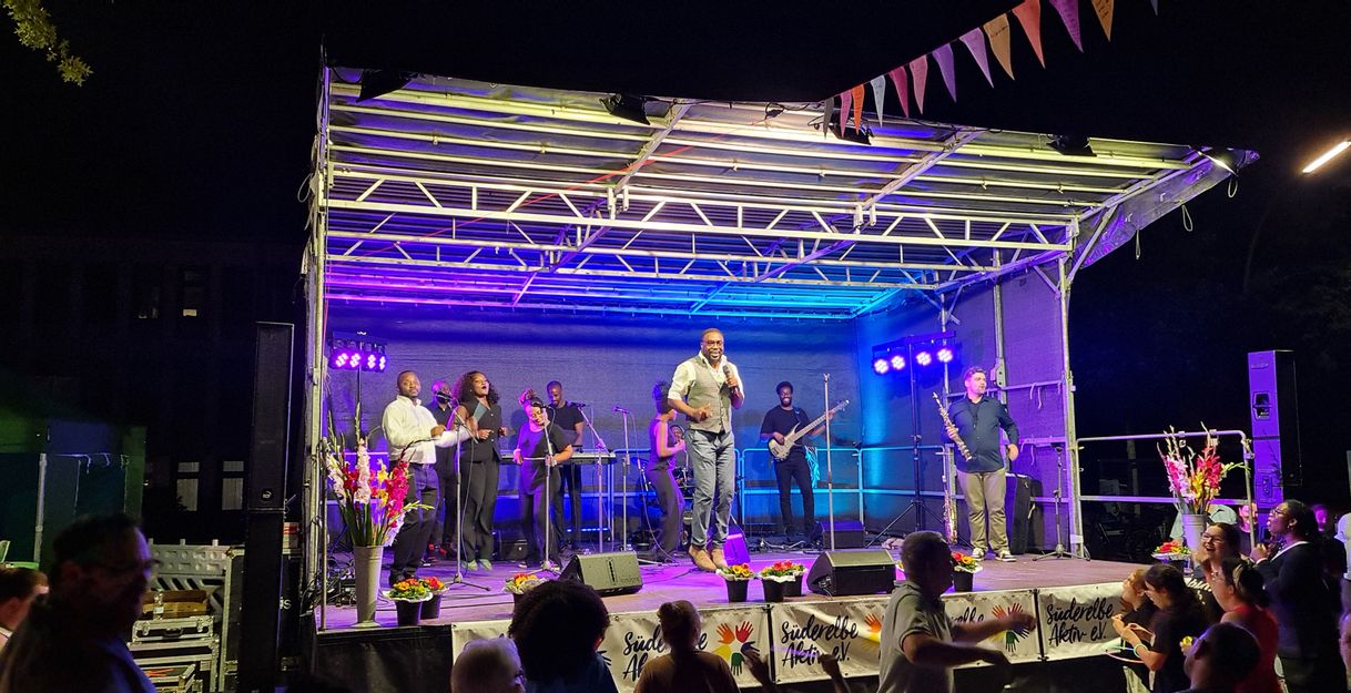 Afro Gospel Voices und Band auf der Bühne in Abendlicher Stimmung.