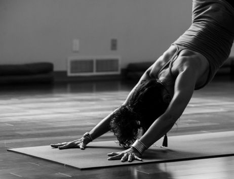 Eine Person in einer Yoga-Pose auf einer Matte in einem Raum.