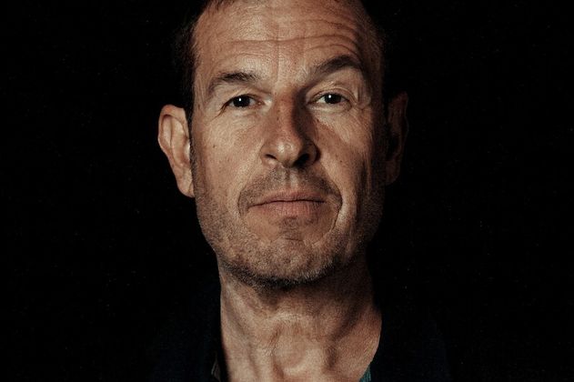 Porträt eines Mannes vor schwarzem Hintergrund.