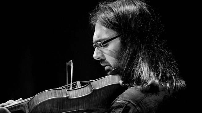 Ein Musiker spielt konzentriert Geige in einem Schwarz-Weiß-Foto.