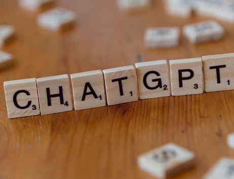 Holzbuchstaben auf einem Tisch bilden das Wort 'CHATGPT'.
