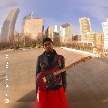 Ein Musiker mit Gitarre steht vor einer städtischen Skyline.