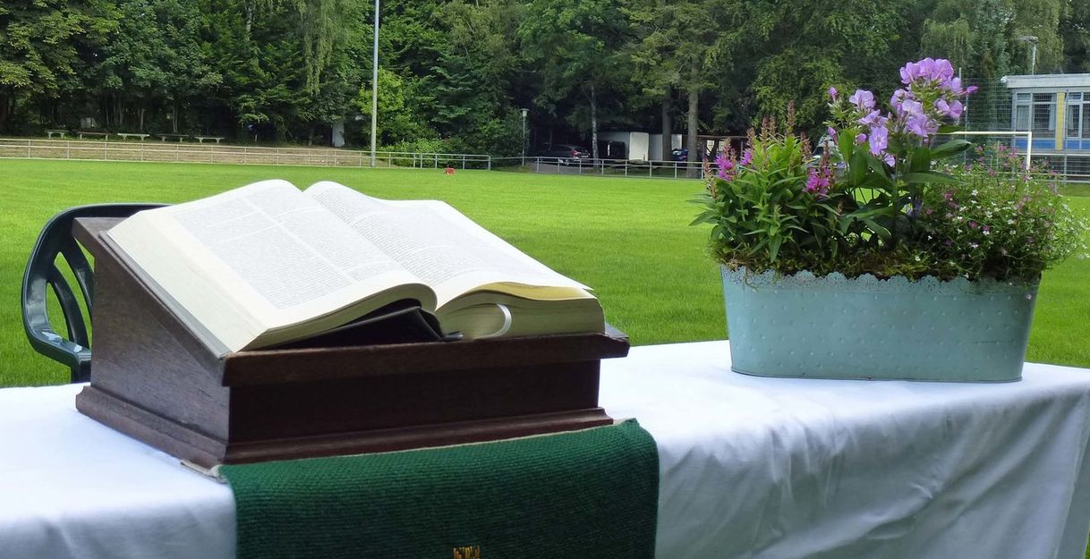 Aufgeschlagene Bibel und Blumenkorb auf einem Altar auf dem Fußballfeld
