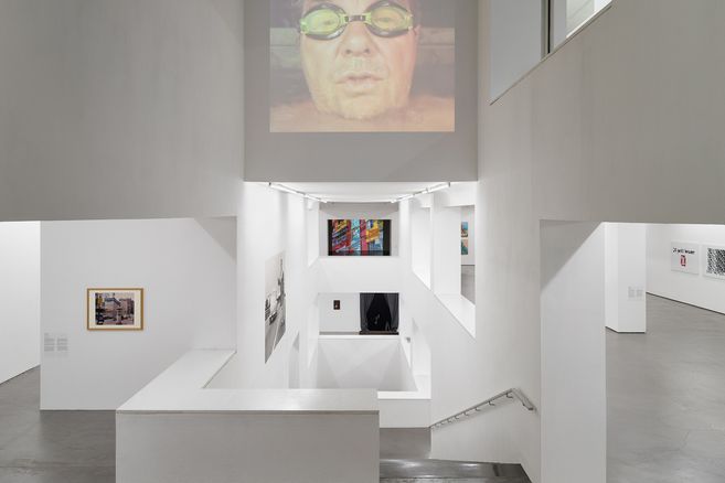 Innenansicht eines modernen Museums mit weißen Wänden und Kunstwerken an den Wänden.
