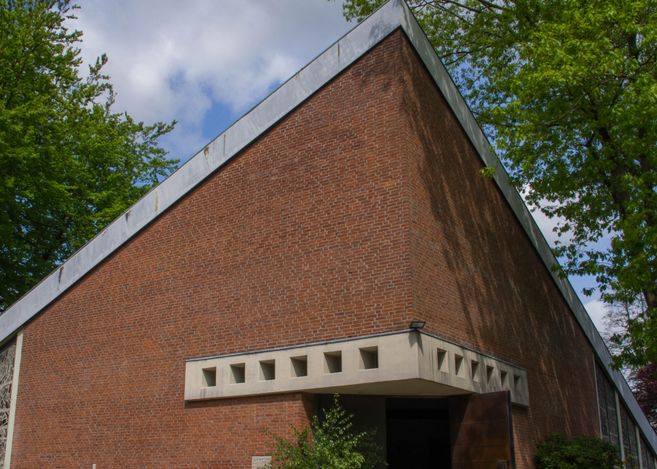 Backsteingebäude mit modernem Design und geometrischen Formen, umgeben von Bäumen.
