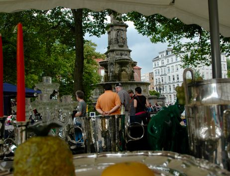 Flohmarktstand und Brunnen im Hintergrund mit Bäumen