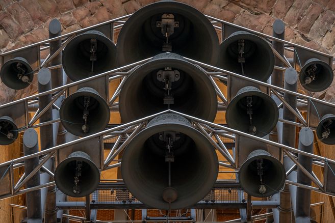 Nahaufnahme eines Glockenspiels mit mehreren großen und kleinen Glocken in einem Metallrahmen.