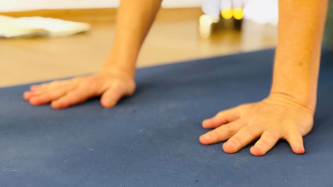Nahaufnahme von Händen auf einer Yogamatte in einer Yoga-Pose.