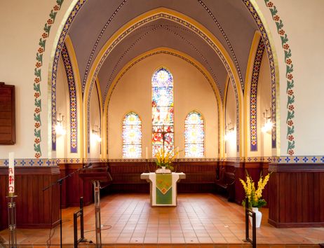 Innenraum der Martinskirche mit Altar, farbigen Spitzbogenfenstern, Gewölbe und Blumenarrangements; kein Gottesdienstbesuch zu sehen.