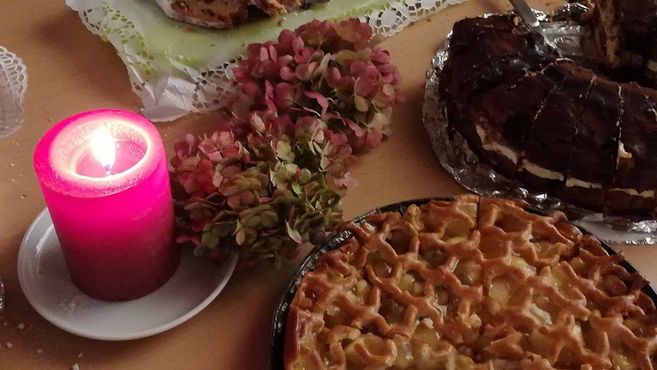 Kerze, Blumen und Kuchen auf einem Tisch.