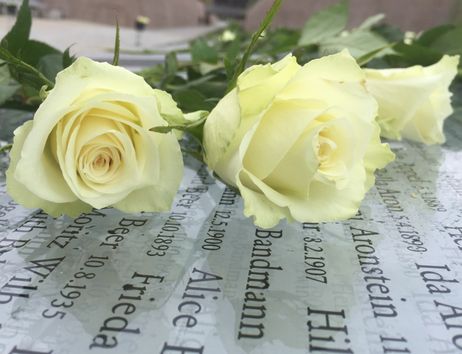 Zwei Blumen auf einer Gedenktafel mit eingravierten Namen