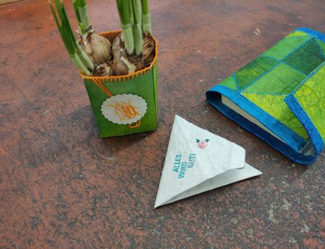 Blumentopf in Grün&Orange aus Tetra Pak. Eine Buchhülle in Blaugrün und ein dreieckiges Lesezeichen