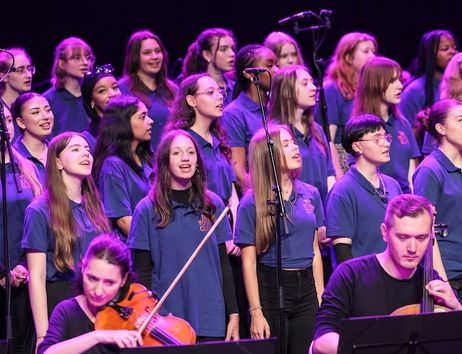 Ein großes Orchester und ein Chor führen gemeinsam auf einer Bühne auf.