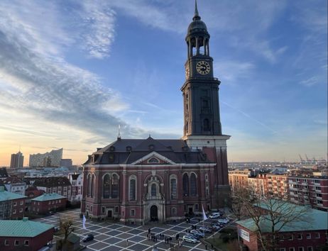 St. Michaelis Kirche in Hamburg bei Sonnenuntergang mit der Elbphilharmonie im Hintergrund.