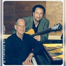 Zwei Männer, einer mit Gitarre und einer am Klavier, in einem Musikstudio.
