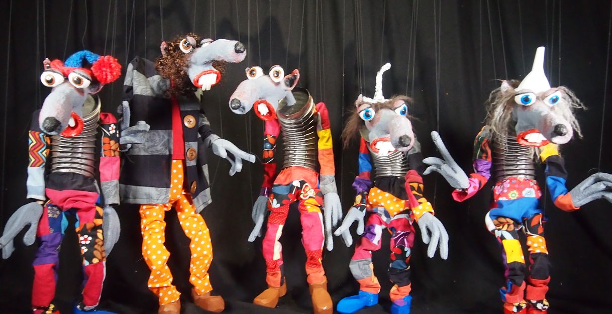 Fünf bunte Puppen mit großen Augen und langen Nasen vor einem schwarzen Hintergrund.