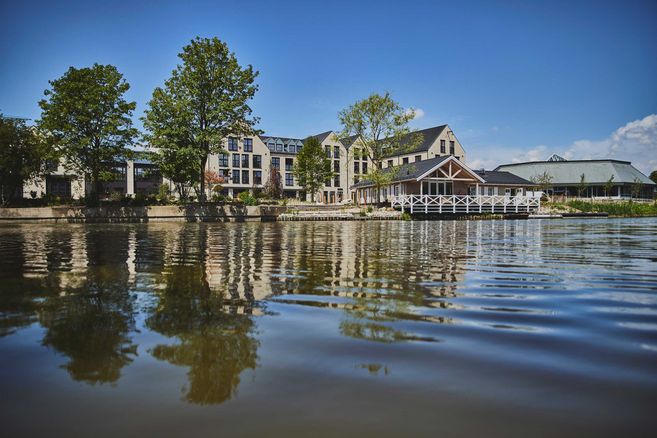 Gebäude am Flussufer mit Bäumen und klarem Himmel.