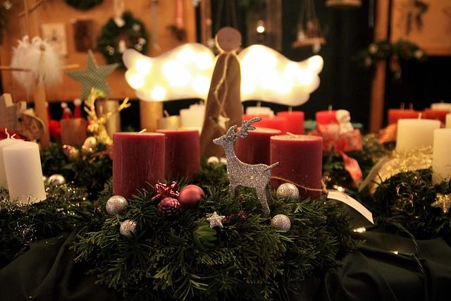 Weihnachtliche Dekoration mit Adventskranz, Kerzen und Engel auf einem Markt.