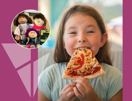 Ein Mädchen isst ein Stück Pizza. Im Hintergrund sind drei Puppen zu sehen.