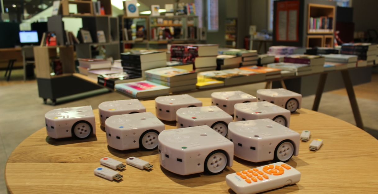 Mehrere kleine Roboter auf einem Tisch in einem Buchladen.