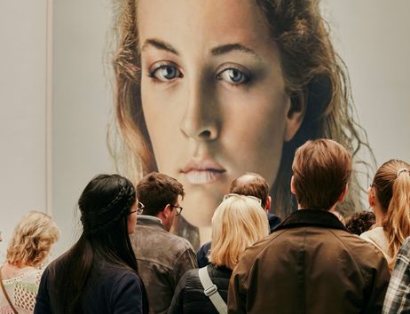 Besucher betrachten ein großes Porträt einer Frau in einer Ausstellung.