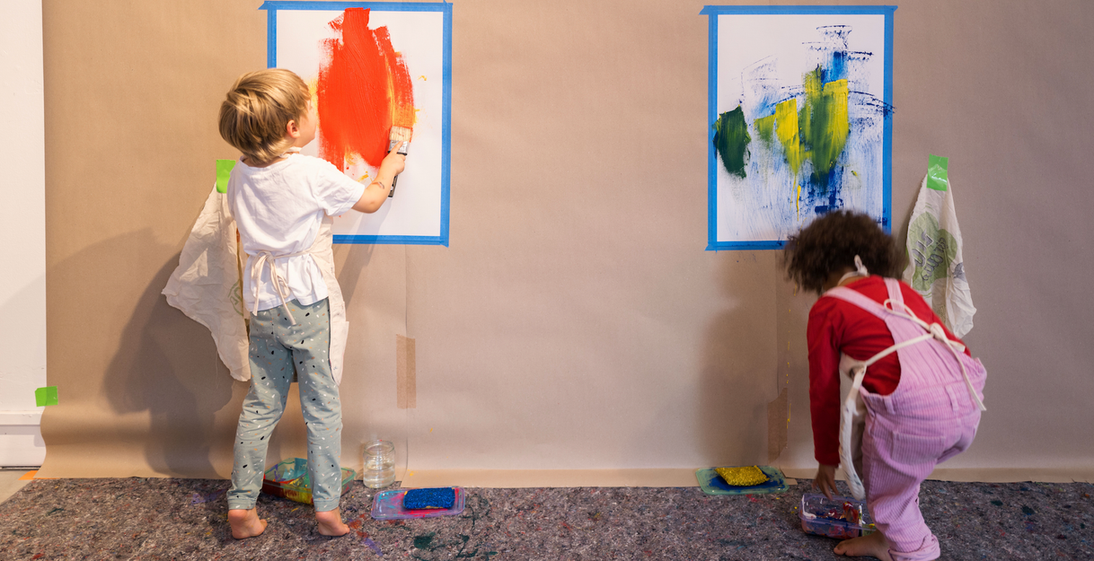Zwei Kinder, die großformatig mit Farbe und verschiedenen Werkzeugen experimentieren.