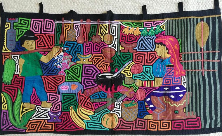 Buntes Mola-Textil mit traditionellen Mustern und Figuren, die eine Küchenszene darstellen.