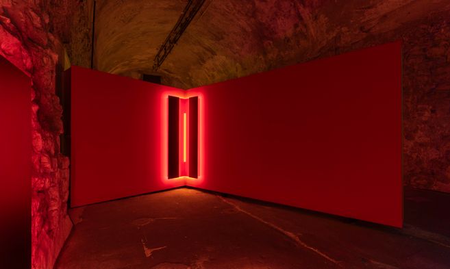 Roter Ausstellungsraum in einem Gewölbe mit leuchtender Lichtinstallation in der Ecke, Teil von „Joining Light“ von Yoana Tuzharova.