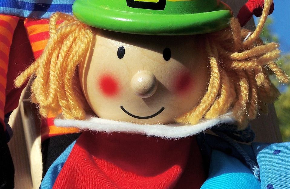 Nahaufnahme einer bunten Handpuppe mit grünem Hut und rotem Umhang.