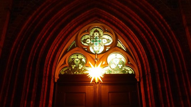 Beleuchtetes Kirchenfenster mit Weihnachtsstern.