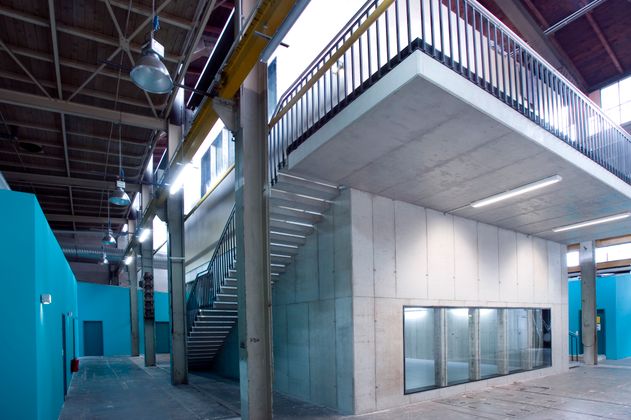 Innenansicht eines modernen Industriegebäudes mit Betonwänden, Treppe und blauen Wänden.