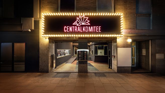 Eingang des Centralkomitee mit leuchtendem Schild und Lichtern.