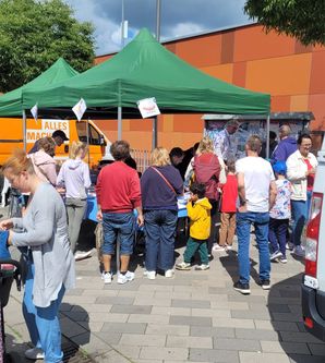 Besucher am Stand von Süderelbe Aktiv e.V., es gibt Bratwurst,Kuchen und Getränke.