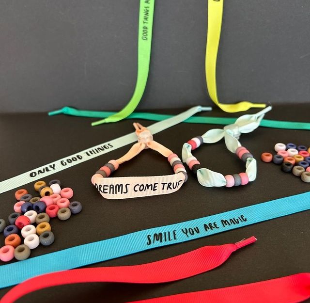 Bunte Armbänder mit inspirierenden Botschaften und Perlen auf schwarzem Hintergrund.