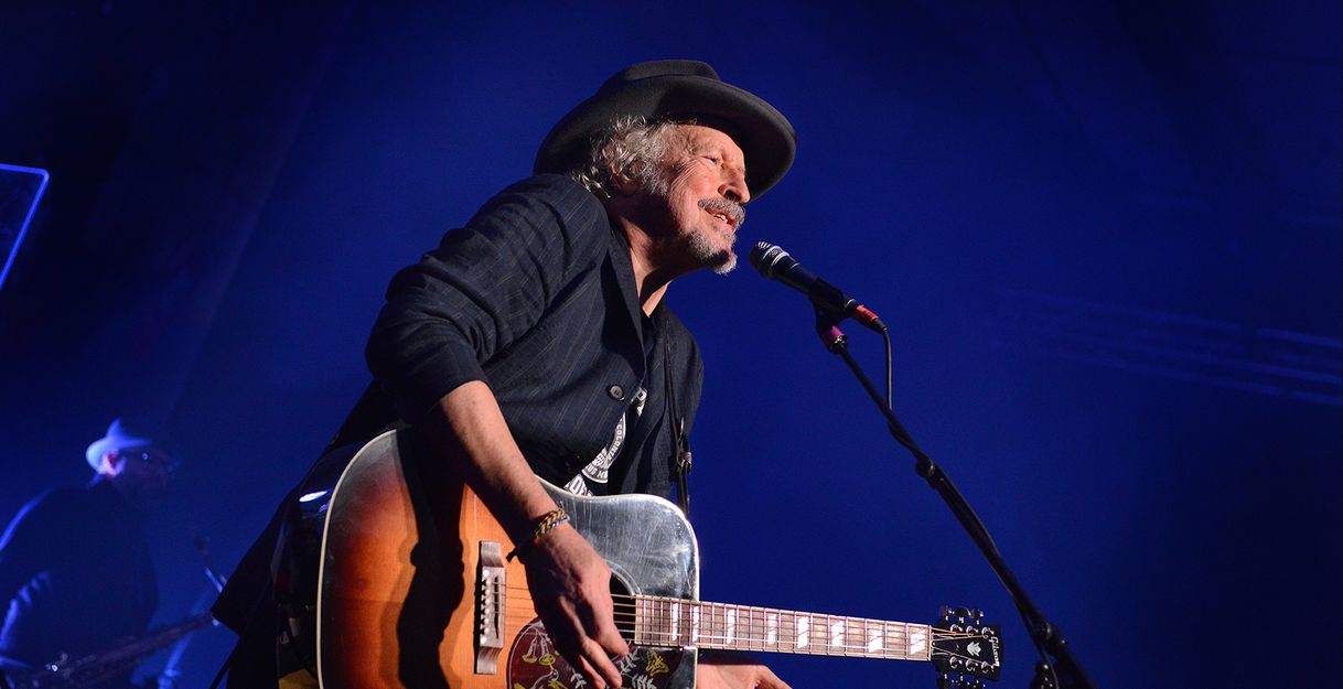 Musiker mit Gitarre singt auf der Bühne.
