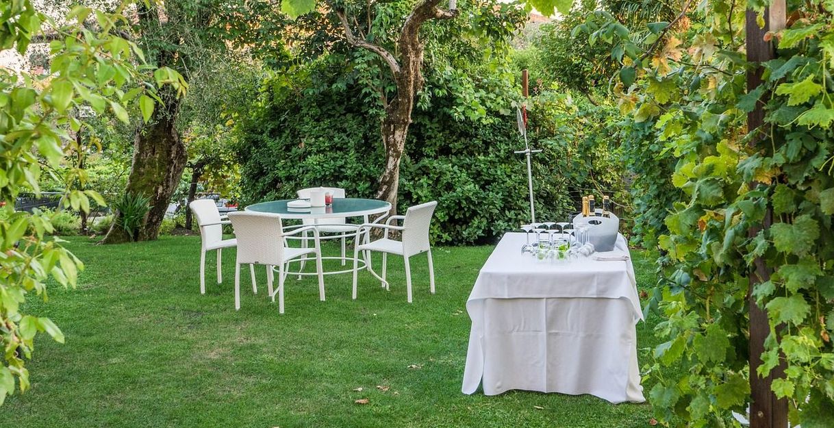 Ein Tisch mit weißen Stühlen und ein Buffet-Tisch im Garten, umgeben von üppigem Grün.